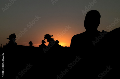 silhouette of firefighters on background of sunset
