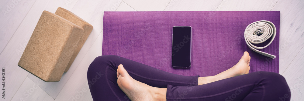 Yoga woman using mobile phone panoramic banner top view of cellphone on exercise mat and blocks, stretching strap. - obrazy, fototapety, plakaty 