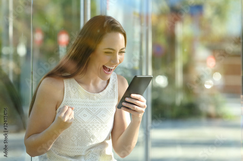 Excited commuter checking phone sitting in a bus stop photo