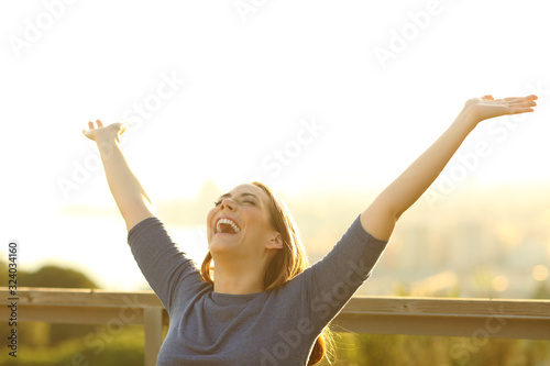 Happy woman on a bench raising arms celebrating life photo