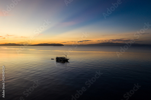 Sunrise silhouettes a diving live aboard ship in Raja Ampat, Indonesia. This region is thought to be the center of marine biodiversity and is a popular area for diving and snorkeling.