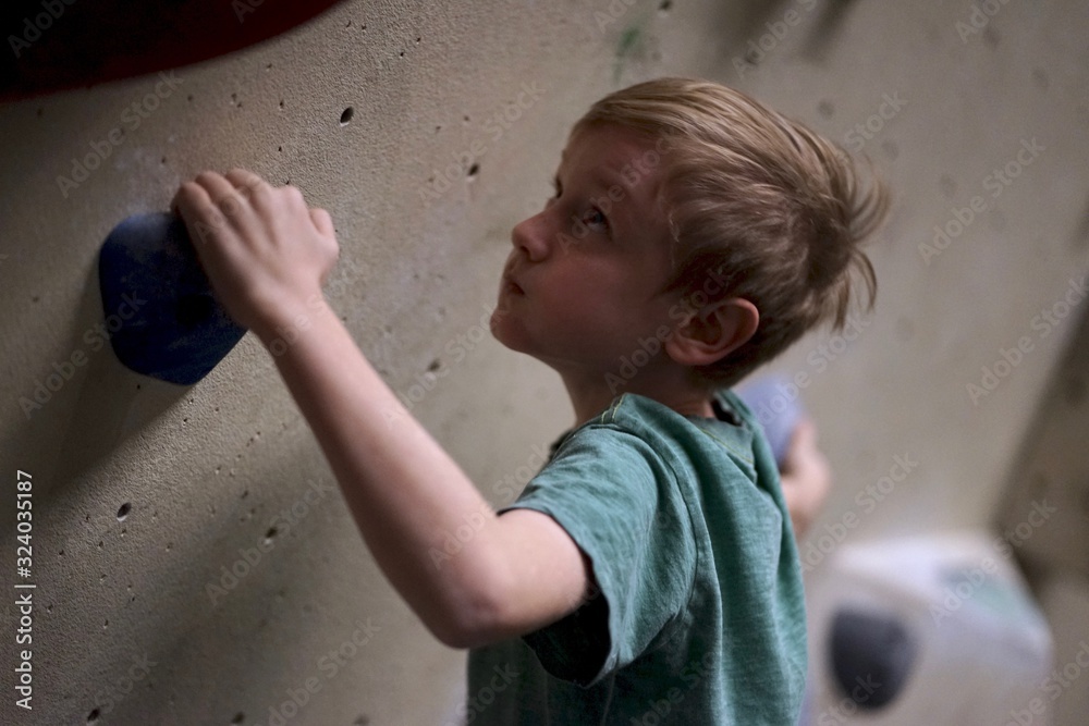 Fotografie Boy climbing bouldering in boulder hall