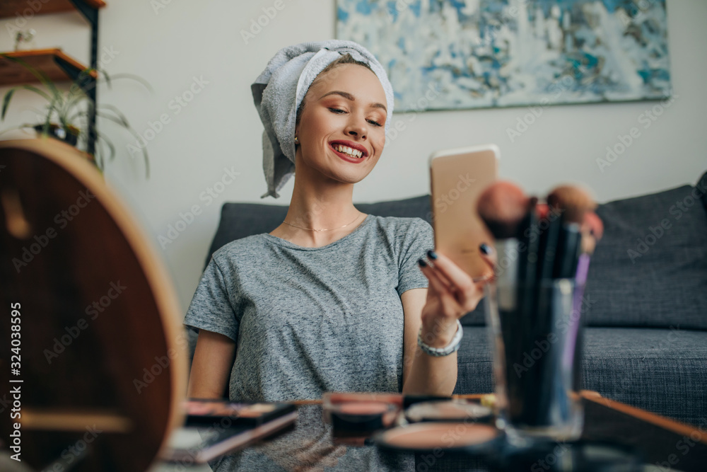 Young woman in her apartment creating a make up selfie