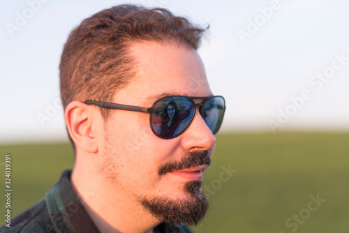 Spring portrait of attractive man with woman in reflection in outdoors with sunglasses