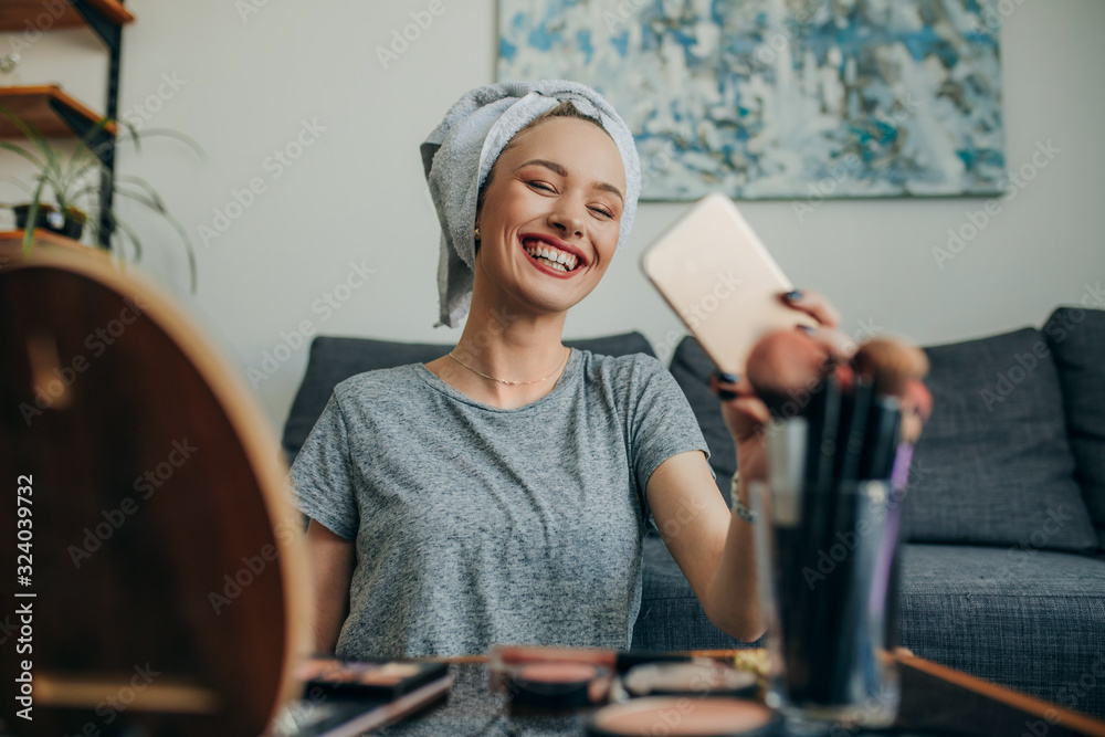 Young woman in her apartment creating a make up selfie