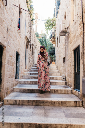 Portrait of beautiful woman with hijab walking on stairs in old narrow street, in Dubrovnik, Croatia. 