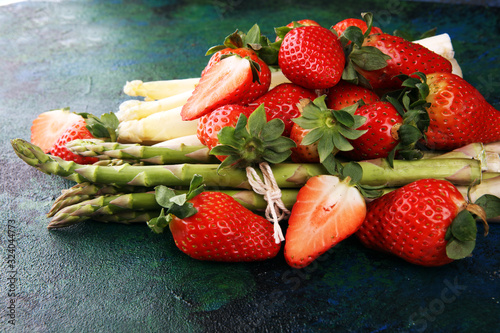 White and green asparagus with strawberries on rustic background
