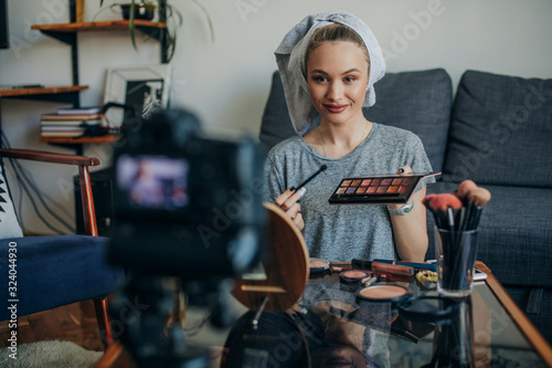 Young woman showing her make up palette. Young social media influencer filming her make up routine