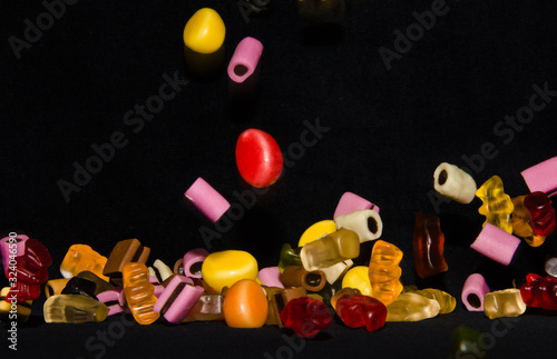 Many sweet and colourful candies are falling down to the table