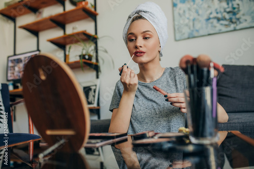 Young woman in her apartment doing her make up