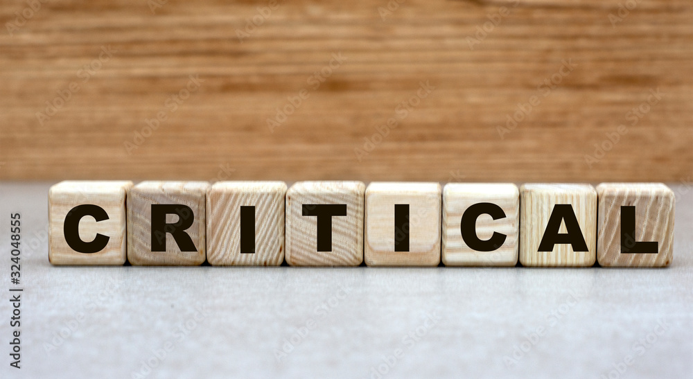 the concept of the word critical on cubes on a light wooden background the concept of the word critical on cubes on a light wooden background