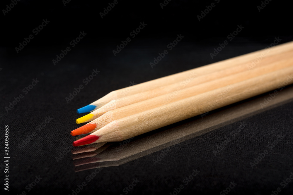 Obraz premium Multi-colored wooden pencils. Dark black background. Natural materials. Stationery. Office tools. Back to school. Education and art. Free space for text.
