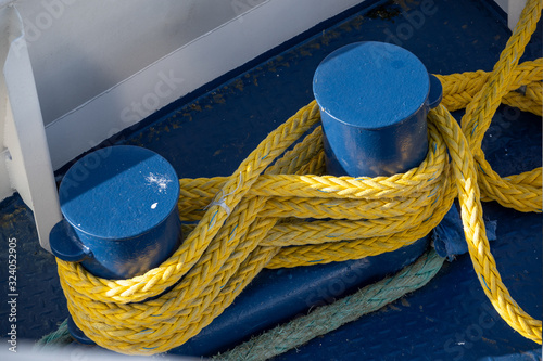 Fotografia yellow ship rope tied around blue mooring bollards on a boat deck