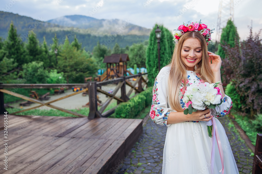 Fototapeta premium beautiful bride in an embroidered dress holds a wedding bouquet