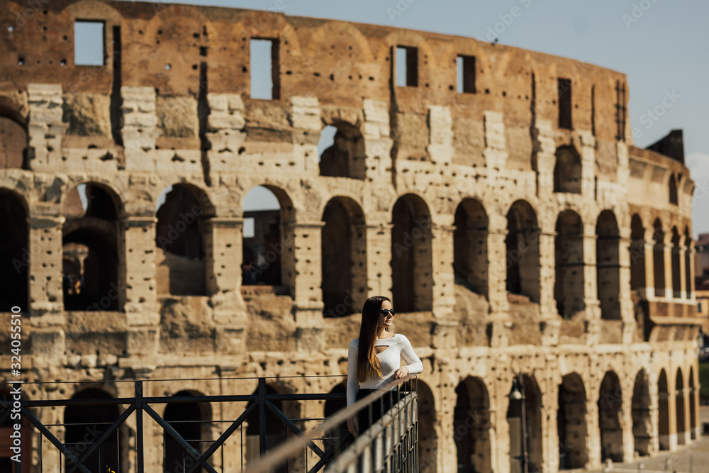 Stylish woman standing near Coliseum, Rome, Italy. Young beautiful woman admiring panoramic view . Young woman enjoy Italian vacation in Europe. 
