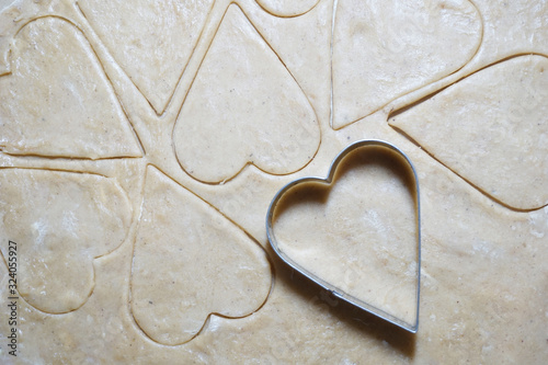 Heart shaped cookie cutters cutting out holiday cookies.