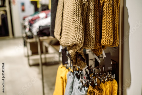 Sweaters in the store.Stack of folded knitted. Yellow green and purple jacket. women's clothing stacked on the heels of the store. © irishasel