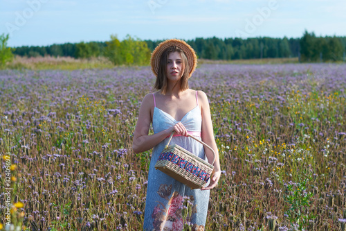 Fototapeta Naklejka Na Ścianę i Meble -  portrait of a beautiful girl in a straw hat.girl with a wicker basket in a field of flowers.happiness.emotions
