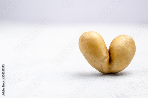 Despicable potatoes in the shape of a heart on a gray background, copy space place