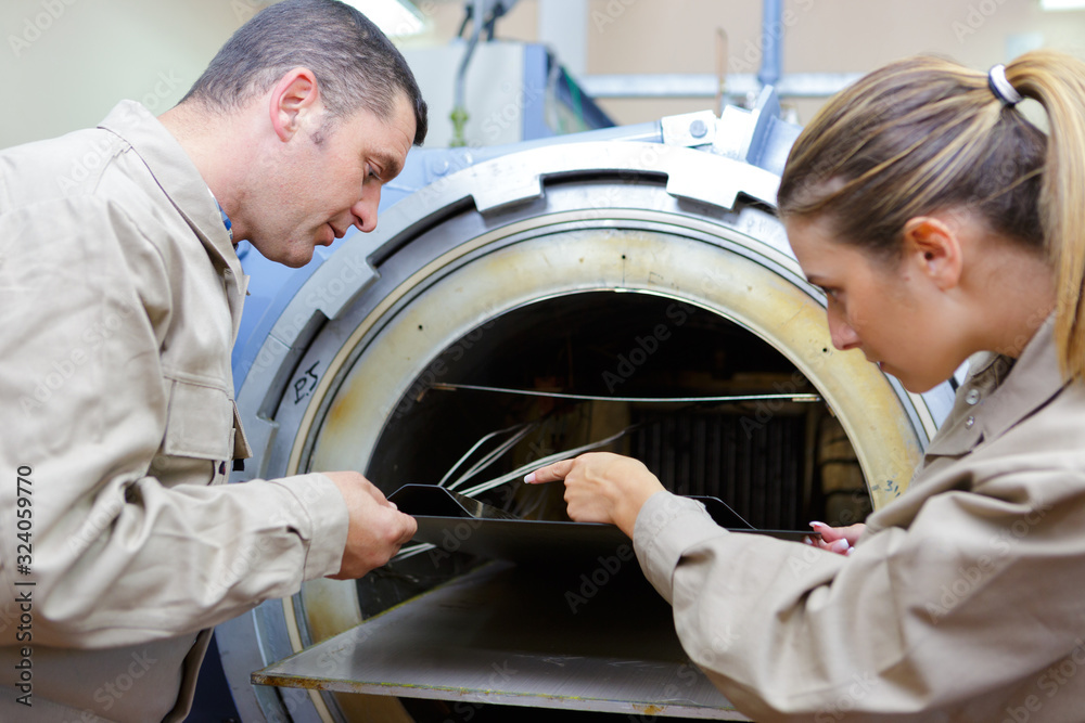 workers taking sheet metal from kiln