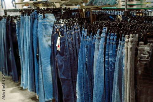 Row of hanged blue jeans. Jeans store in a shopping center. Denim sales. Blue pants. Shopping for women. Moll.