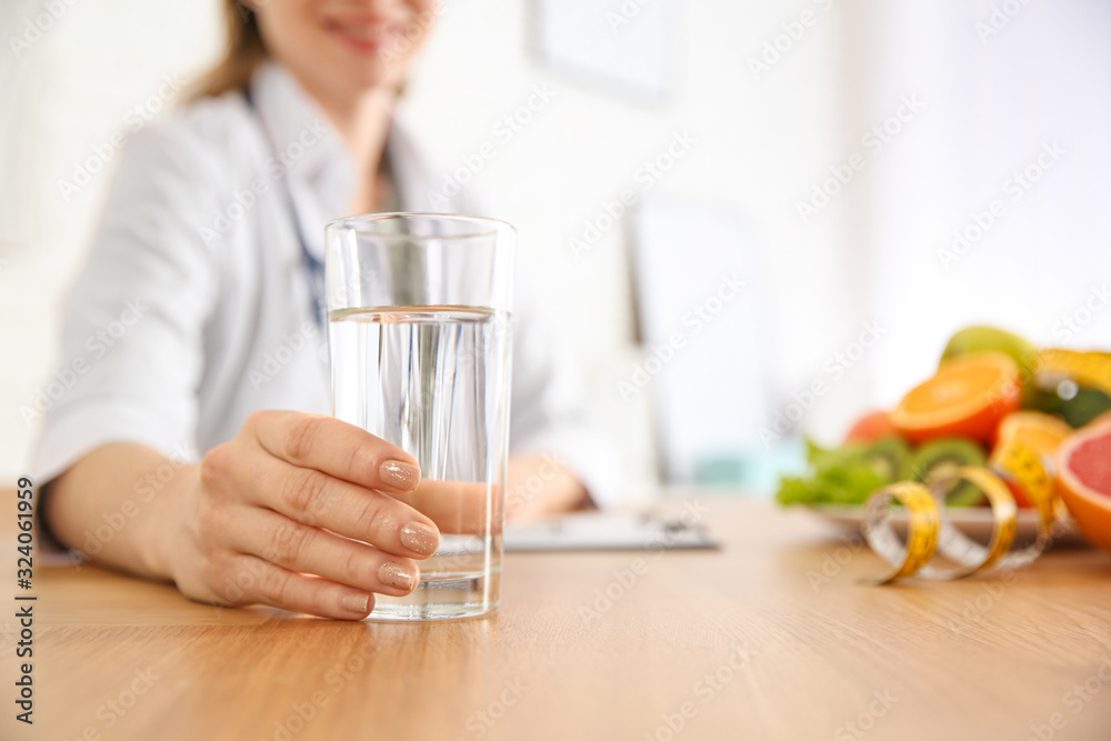 Nutritionist with glass of water at desk in office, closeup Nutritionist with glass of water at desk in office, closeup