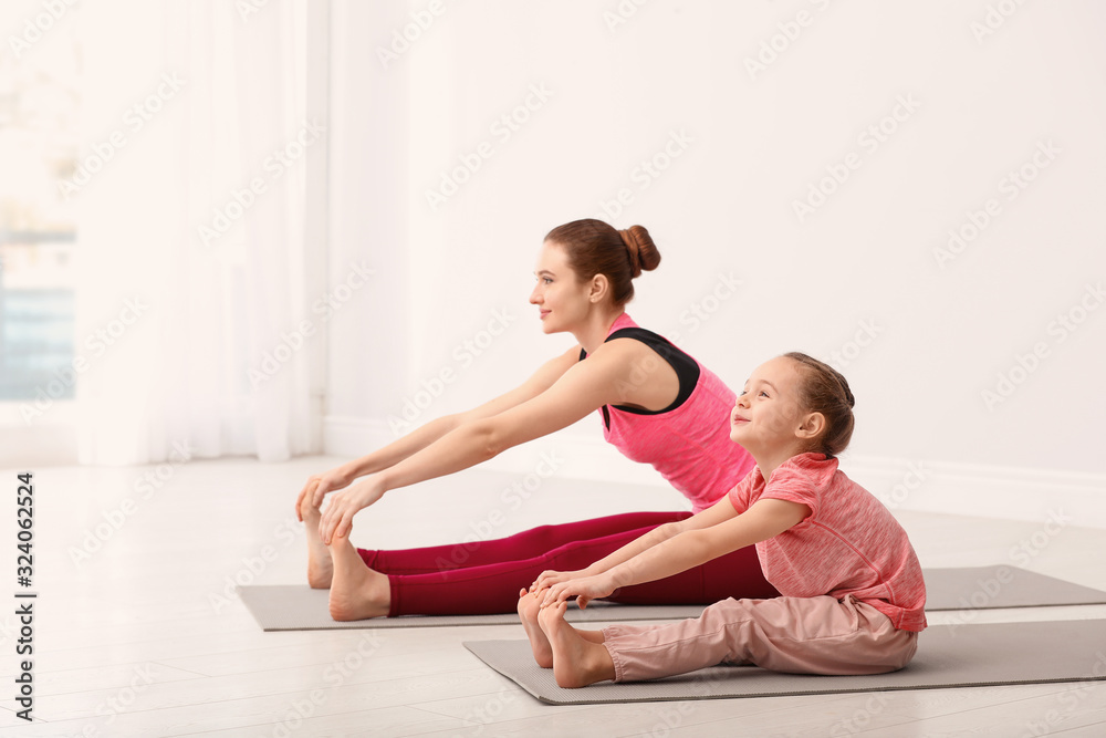 Young mother with little daughter practicing yoga at home Young mother with little daughter practicing yoga at home