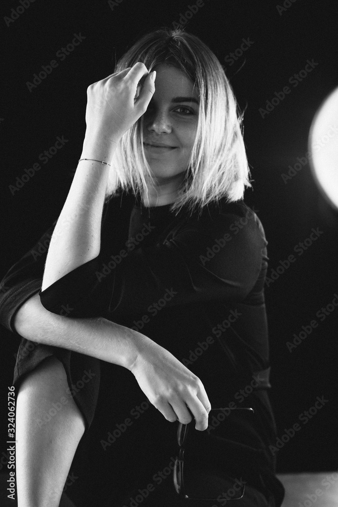beautiful girl in a black suit sits on a chair and a desk with a laptop beautiful girl in a black suit sits on a chair and a desk with a laptop