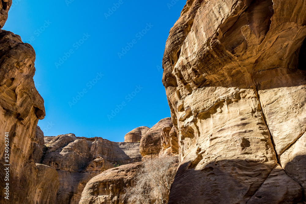 Breathtaking natural gorge called Al-Siq, carved in the red cliffs by the water flow, Petra ancient city complex and tourist attraction, Hashemite Kingdom of Jordan. Sunny winter day, cloudless sky