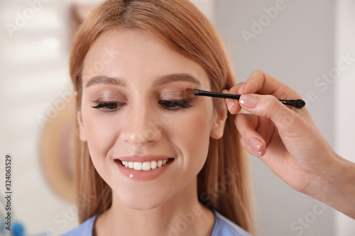 Professional makeup artist working with beautiful woman in salon