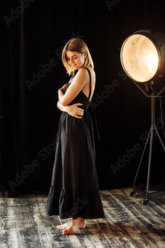 beautiful girl in a black dress sits on a chair on black background