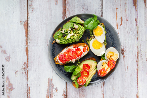 Sweet potato toasts with avocado, boiled eggs, tomatoes and sesame seeds on white rustic background. Healthy meal concept. Clean eating, Pescetarian food, top view