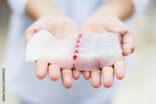 High angle close up of hands holding fresh fillet of white fish, Barramundi, Asian Sea Bass. photo