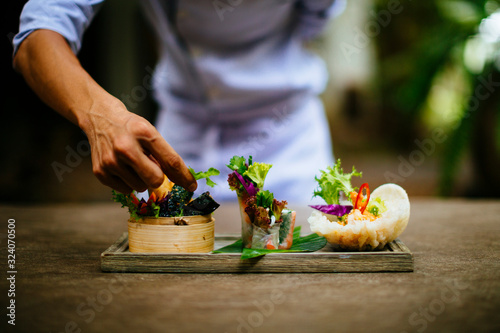 Close up of chef putting the final touches on a dish of salads and spring rolls.,Saigon