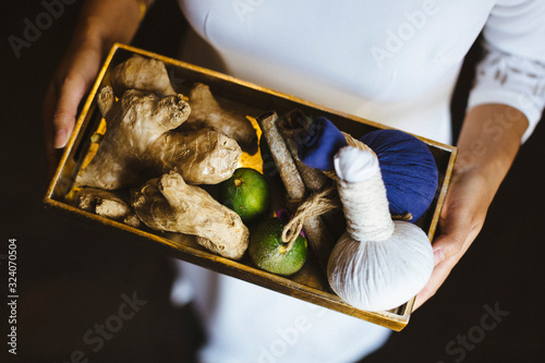 High angle view of person holding tray with fresh ginger and limes and herbal compresses.,Saigon photo