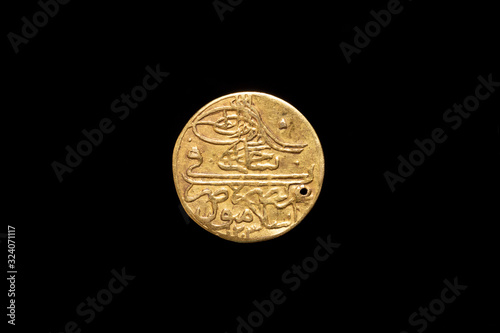 Old Ottoman Empire gold coin with a hole, obverse. Isolated on black background