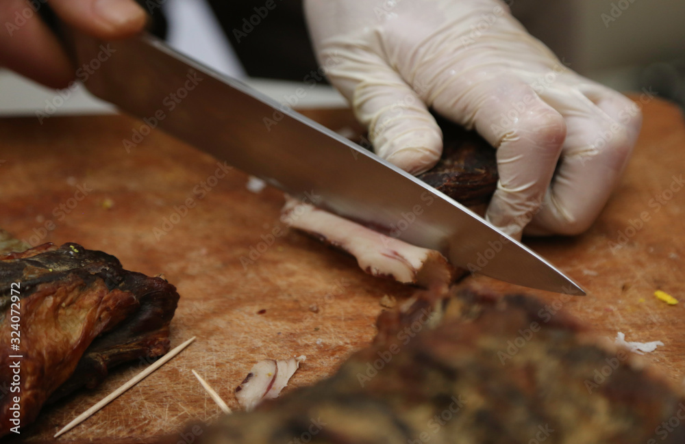 Obraz premium Cutting smoked lamb meat