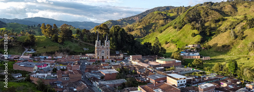 Typical Antioquia Village with Big Catedral Surrounded of Green Hills of Pastures and Mountains Aerial View in Belmira, Antioquia / Colombia photo