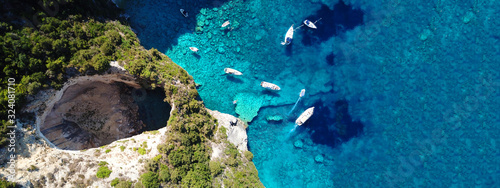 Aerial drone ultra wide photo of tropical white rocky bay of blue lagoon with turquoise clear waters, white volcanic caves and sail boats docked, island of Paxos, Ionian, Greece