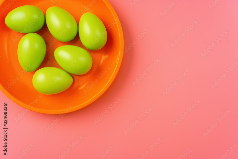 Close up of green Easter eggs in a bright plate on vibrang orange and red background Close up of green Easter eggs in a bright plate on vibrang orange and red background