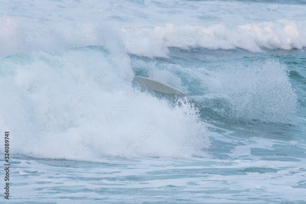 Obraz premium Surfer swallowed by a big wave on a beach on the north coast of Spain