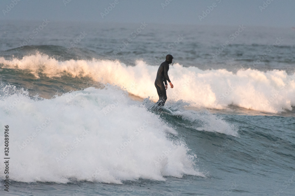 Unrecognizable surfer on the crest of the wave with his back to the camera Unrecognizable surfer on the crest of the wave with his back to the camera