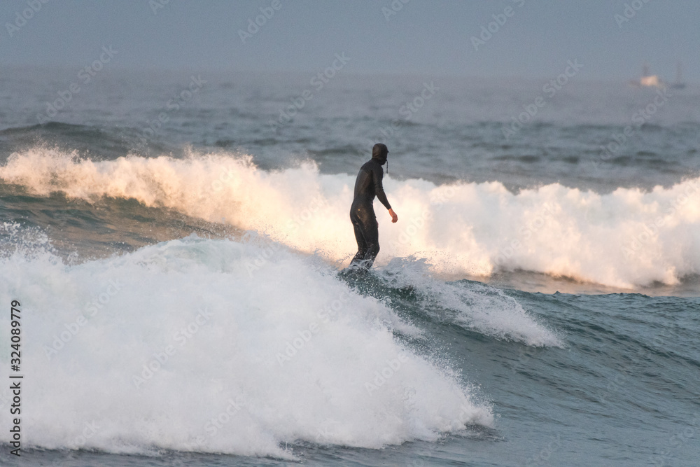 Unrecognizable surfer on the crest of the wave with his back to the camera Unrecognizable surfer on the crest of the wave with his back to the camera
