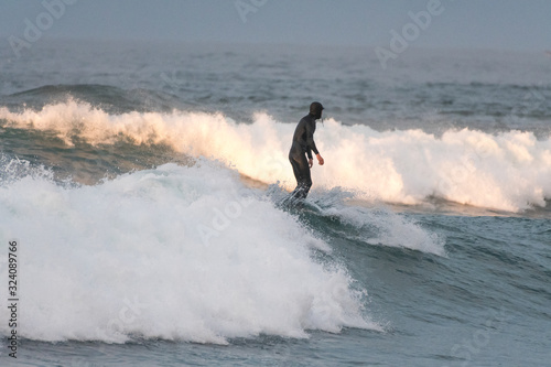 Unrecognizable surfer on the crest of the wave with his back to the camera