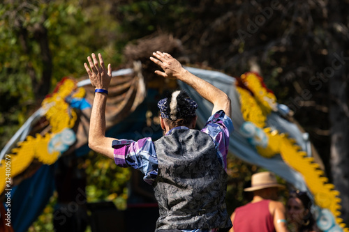 A close up and rear view of an older man dancing with arms in air during a festival celebrating earth, culture and alternative communities. Copy space to sides