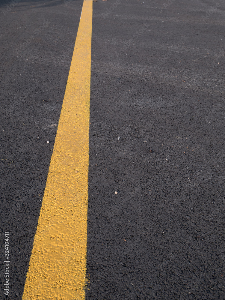 Yellow line across dark asphalt