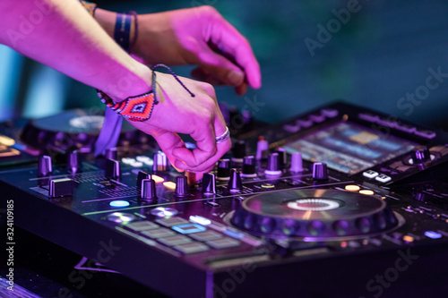 A close up shot on the hands of a music DJ using an electronic CDJ deck to perform a set during a festival celebrating cultural music and earth. Copy space to right