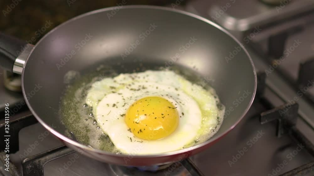 Seasoning being poured on top of delicious egg being fried in teflon frying pan Seasoning being poured on top of delicious egg being fried in teflon frying pan