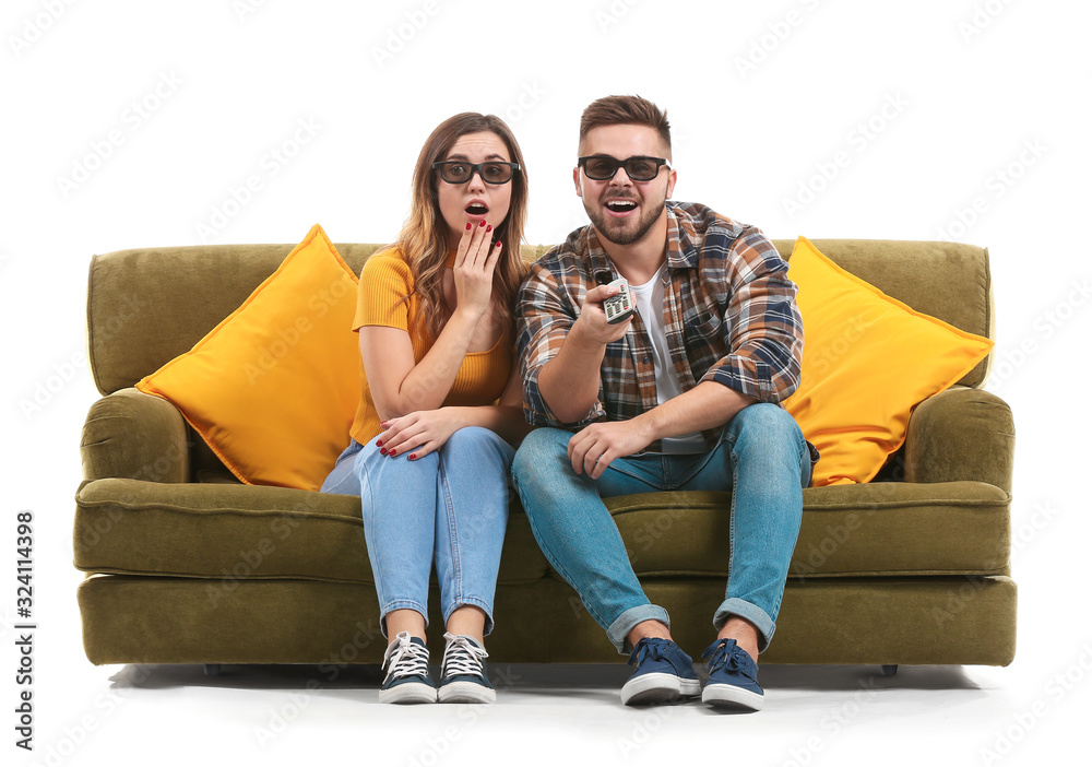 Young couple watching TV while sitting on sofa against white background Young couple watching TV while sitting on sofa against white background