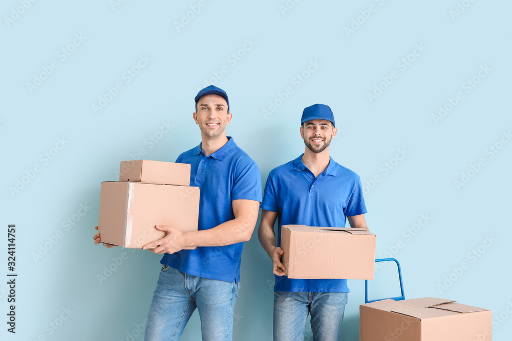 Delivery men with boxes on color background Delivery men with boxes on color background